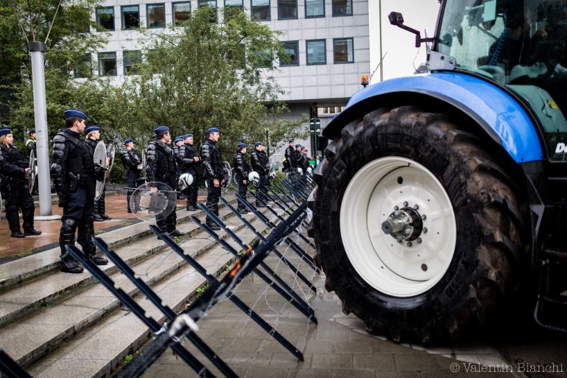 Police wearing riot gear and holding shields stand in front of a barricade as they protect european buildings in Brussels  during a protest by EU dairy farmers. September 7th, 2015. © Valentin Bianchi